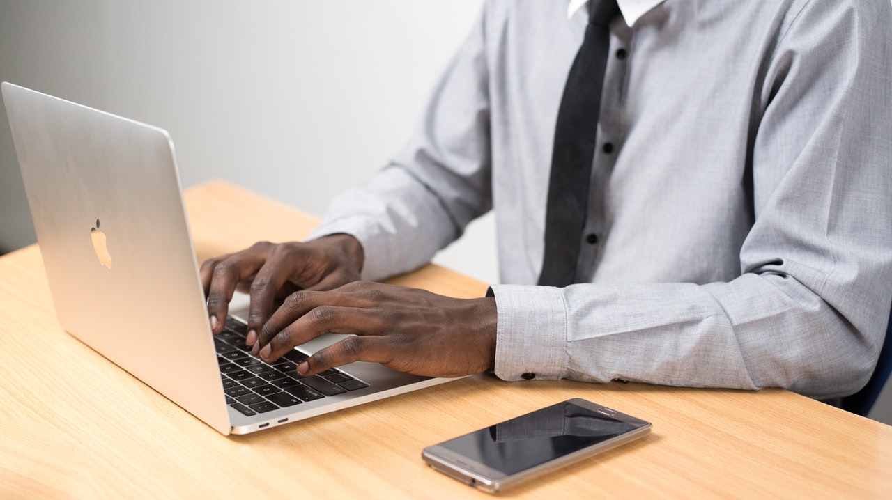 man-sitting-in-front-of-table-using-laptop-beside-phone.jpg